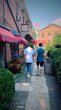 two people walking down a sidewalk in a small town